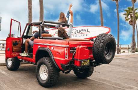 Friends in a red Bronco with a surfboard at the beach near StorQuest Self Storage in Santa Monica, California