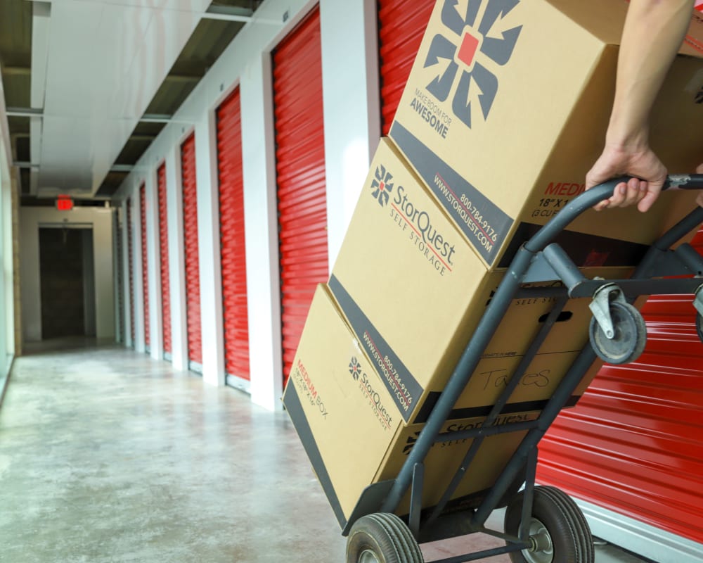 A StorQuest Self Storage customer uses a complimentary hand truck to move a stack of large boxes