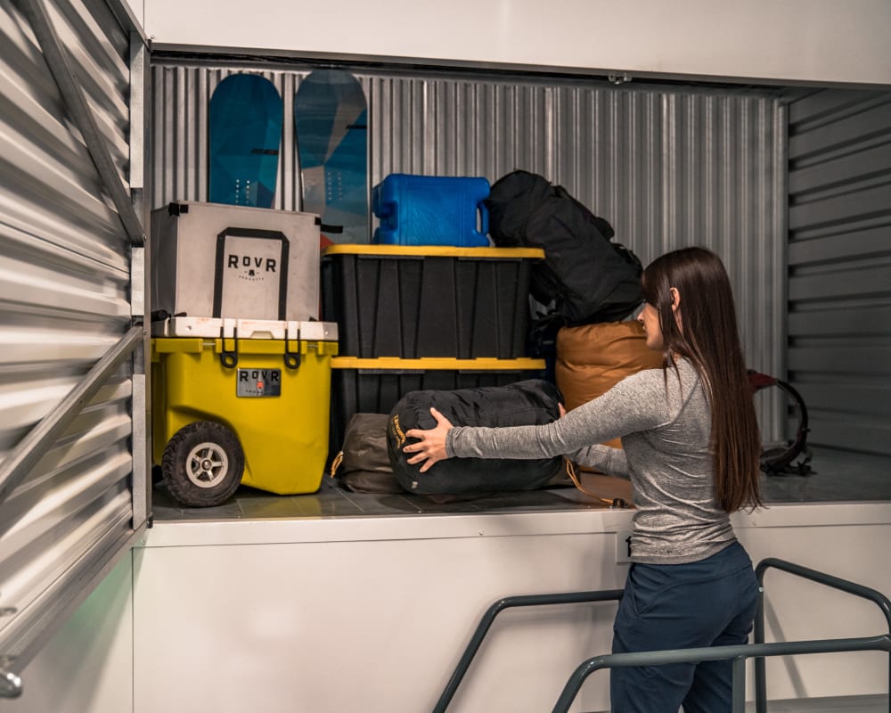 A woman stores seasonal camping gear in a storage locker at StorQuest Self Storage