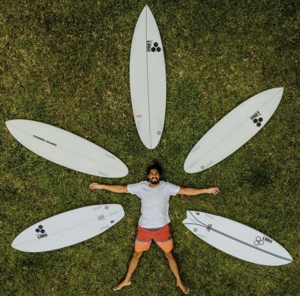 Dr. Cliff Kapono lying on the ground, surrounded by five surfboards