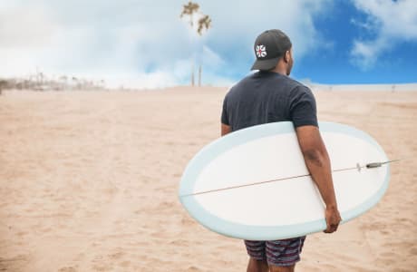Man holding a surfboard on a beach near StorQuest Self Storage in Santa Monica, California