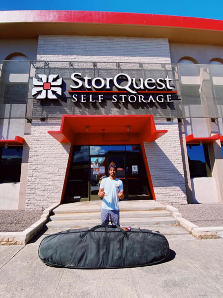 Dr. Cliff Kapono standing in front of a StorQuest Self Storage facility, with a large bag of gear in front of him